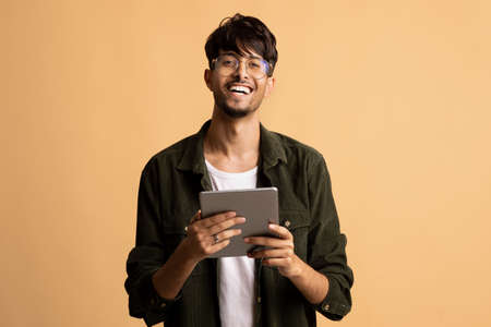 Happy indian guy freelancer using modern digital tabletの写真素材