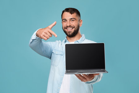 Happy mature attractive european guy show finger at laptop with blank screenの写真素材