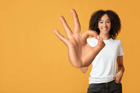 Smiling african american lady wearing in white t-shirt showing OK