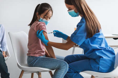 Asian Girl Getting Vaccinated Against Coronavirus In Modern Clinicの写真素材