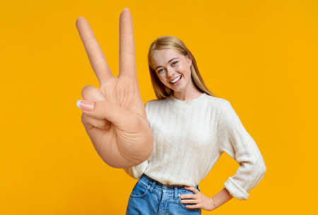 Cheerful young blonde lady showing peace gestureの写真素材