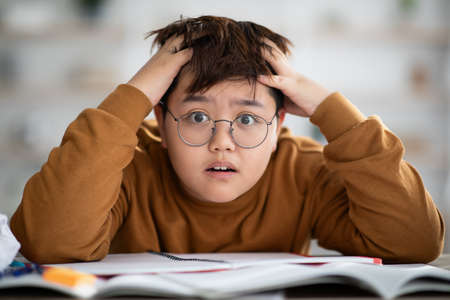 Closeup of shocked chubby chinese boy doing homeworkの写真素材