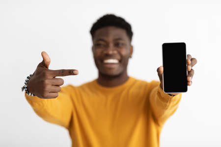 Selective focus on cellphone with empty screen and pointing handの写真素材