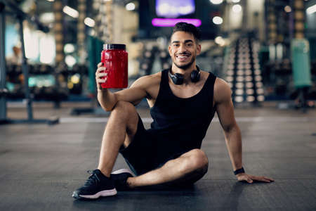 Arab Athlete Posing At Gym With Container Of Protein Whey In Handの写真素材