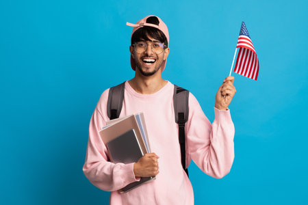 Smiling indian guy student showing flag of USの写真素材