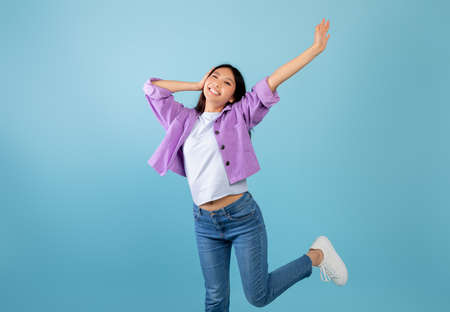 Positive emotions. Young emotional asian lady laughing, feeling happiness, raising hands and expressing joyの写真素材
