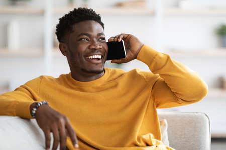 Cheerful african american guy having phone conversation with friend