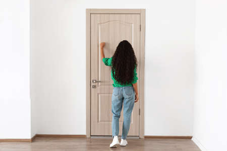 Rear back view of woman knocking on the wooden doorの写真素材