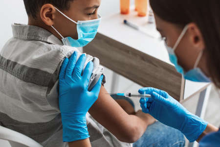 Nurse In Face Mask Injecting Vaccine Vaccinating Boy Indoors, Croppedの写真素材