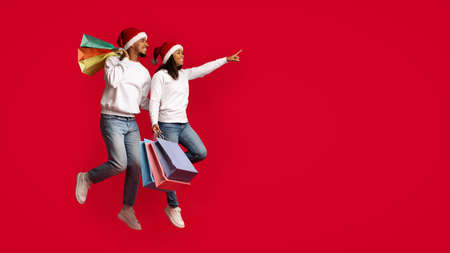 Emotional african american lovers in Santa hats holding shopping bagsの写真素材