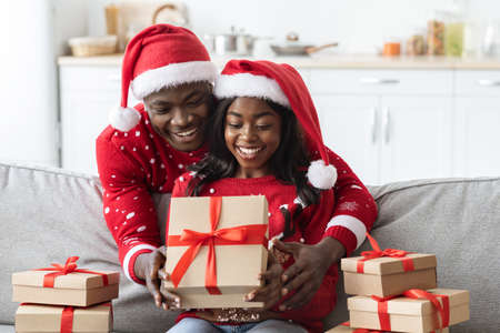 Smiling african american couple opening xmas gifts from relativesの写真素材