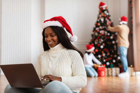 Happy black lady using laptop on Xmas eveの写真素材