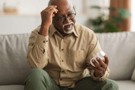 Senior African American Man Holding Medical Pills Reading Instruction Indoorの写真素材