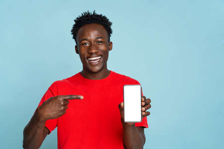 Mobile Offer. Joyful black guy pointing at cellphone with empty white screen
