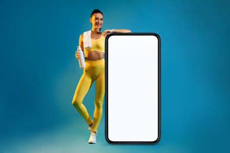 Fitness Woman Leaning On Big Smartphone Screen Over Blue Background