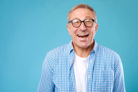 Portrait of happy mature man in glasses posing at studio