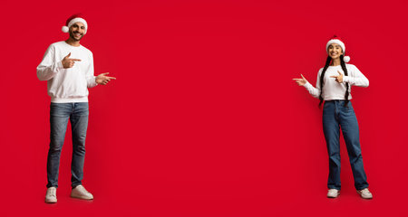 Arab Couple Wearing Santa Hats Pointing At Copy Space In The Middleの写真素材