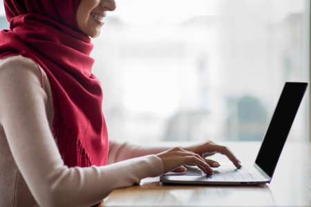 Cropped of woman in hijab using notebook with empty screenの写真素材
