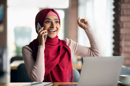 Emotional muslim young woman independent contractor working at cafeの写真素材