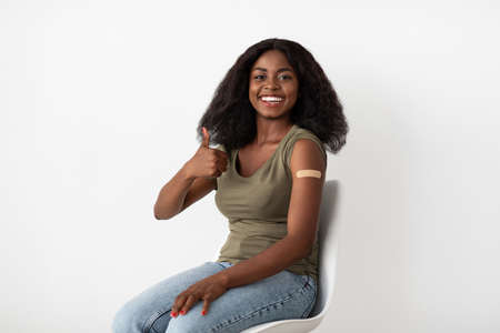 Black woman showing adhesive band on shoulder and thumb upの写真素材