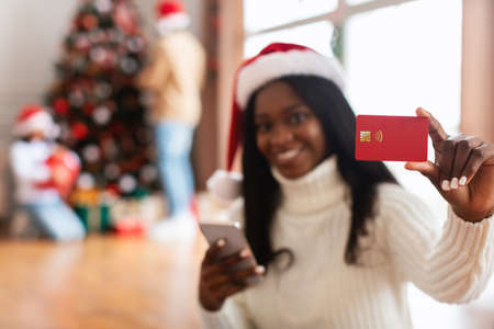 Xmas Online Shopping. Smiling lady using cellphone showing credit cardの写真素材