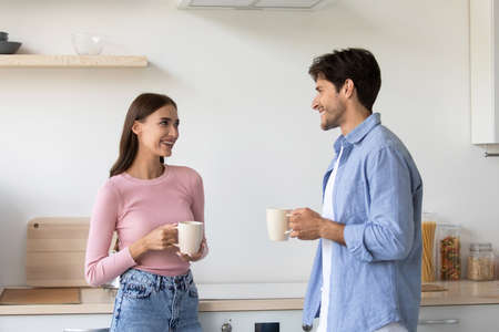 Cheerful millennial european lady and man with cups, communicating and drink coffee in morningの写真素材