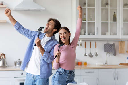 Satisfied happy millennial caucasian male and female sing at imaginary microphone, enjoying danceの写真素材