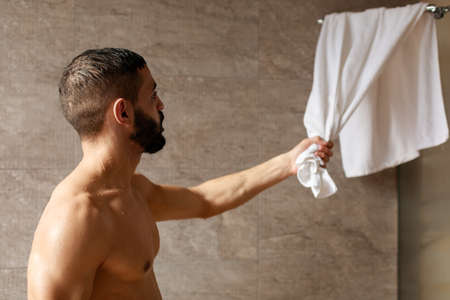 Handsome young Arabic male grabbing towel after showerの写真素材