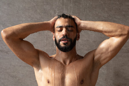 Handsome young Arabic male model taking hot showerの写真素材