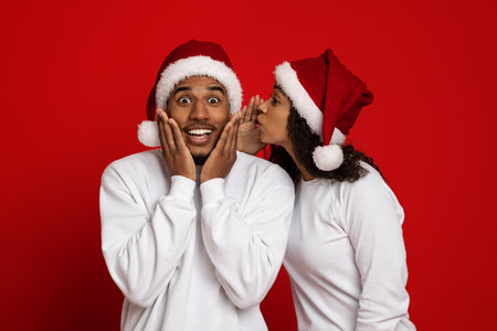 Black lady sharing secrets with her amazed boyfriendの写真素材