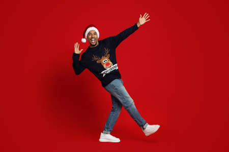 Positive african american man Santa Claus gesturing on red