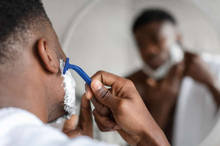 Black Man Shaving Face With Safety Razor In Bathroom, Closeupの写真素材