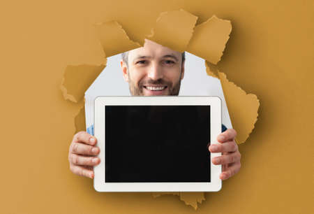 Guy showing empty tablet screen through torn paper
