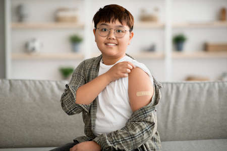 Cute plump korean kid got vaccinated, showing adhesive bandの写真素材