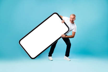 Happy adult man carrying big white empty smartphone screenの写真素材