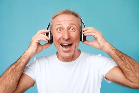 Headshot Portrait Of Excited Mature Man Wearing Wireless Headphonesの写真素材