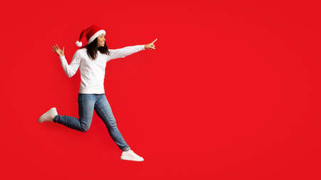 Happy black woman in Santa hat running towards copy spaceの写真素材
