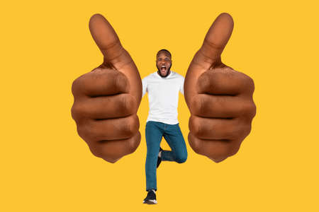 Emotional Black Guy Showing Huge Thumb Ups Over Yellow Backgroundの写真素材