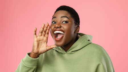 Joyful African Lady Shouting Holding Hand Near Mouth, Pink Backgroundの写真素材