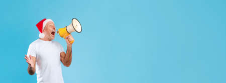 Excited man wearing Christmas hat screaming in megaphone, panoramaの写真素材