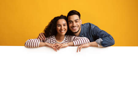 Happy Young Middle Eastern Couple Leaning At Big White Advertisement Boardの写真素材