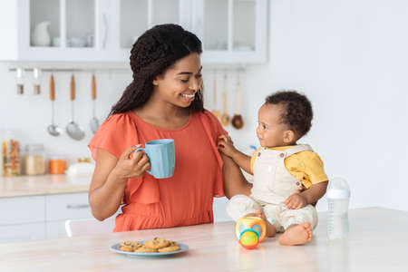 Time With Mom. Cute Black Baby Boy Relaxing With Mother In Kitchenの写真素材