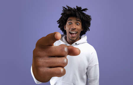 Funky black teen guy pointing index finger at camera, making big I CHOOSE YOU gesture on violet studio backgroundの写真素材