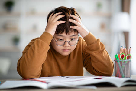 Shocked korean teenager looking at exercise bookの写真素材
