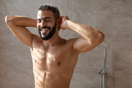 Handsome young Arabic male model enjoying taking hot showerの写真素材