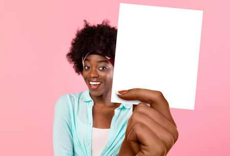 African American Female Holding Blank Card Standing Over Pink Backgroundの写真素材