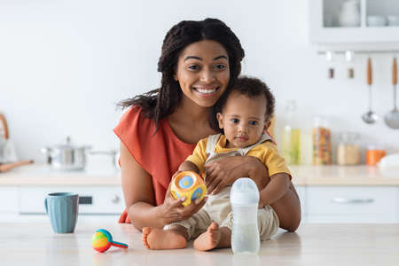 Happy Young African American Mother And Cute Toddler Baby Posing In Kitchenの写真素材