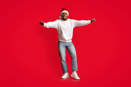Joyful african american guy in Santa hat having funの写真素材