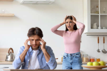 Upset depressive disappointed millennial european lady holding her head with hands swears at sad guyの写真素材