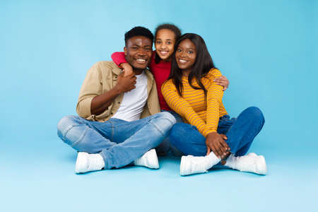 African American girl hugging her smiling mom and dadの写真素材